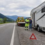 Asistencia en viaje en Europa: qué revisar en tu seguro de camper o autocaravana Autocaravana detenida en una carretera europea con grúa y señal de emergencia durante una asistencia en viaje.