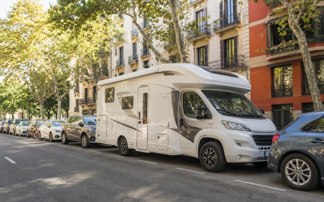 Autocaravana aparcada en una avenida arbolada de la ciudad, compartiendo el espacio público con turismos.